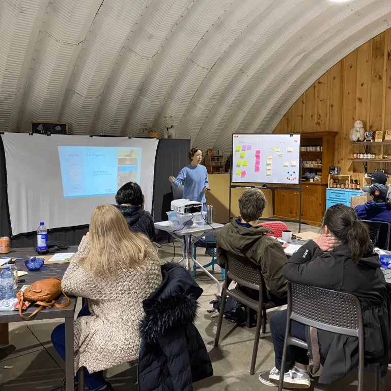 Cheryl facilitating a corporate training session at Udderly Ridiculous Farm Life, presenting on a projector and whiteboard to a group of participants in the farm market store