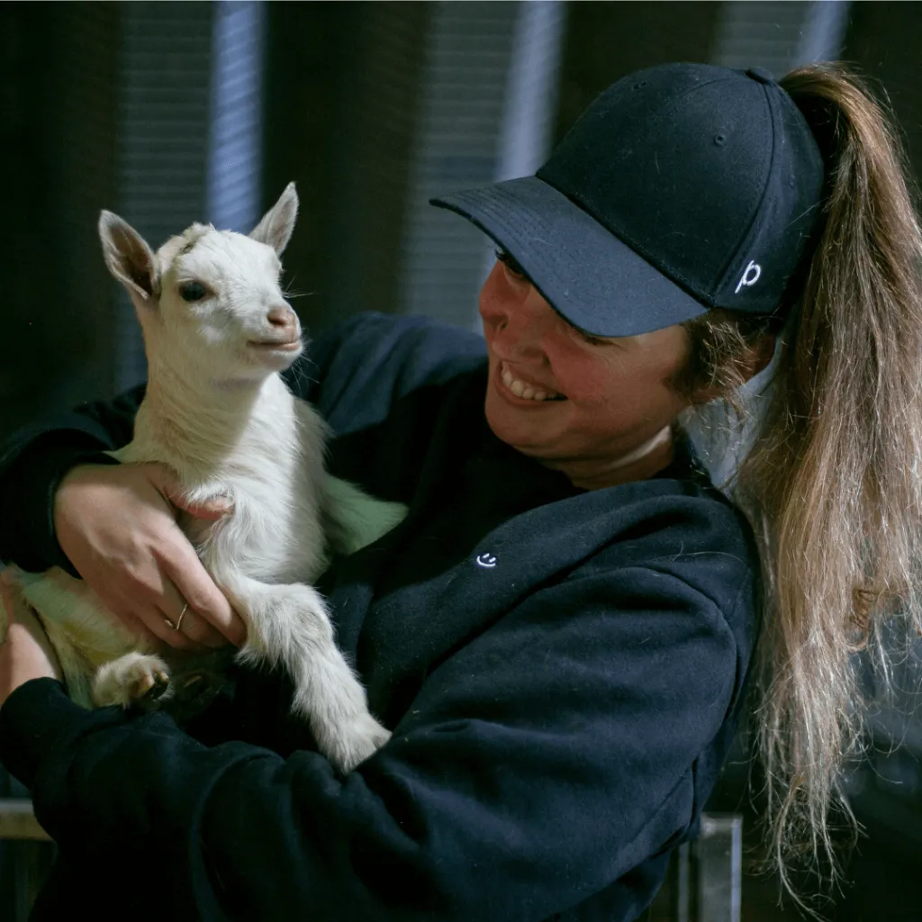 A guest snuggling a young goat during the Goat Cuddles experience inside the goat barn at Udderly Ridiculous Farm Life