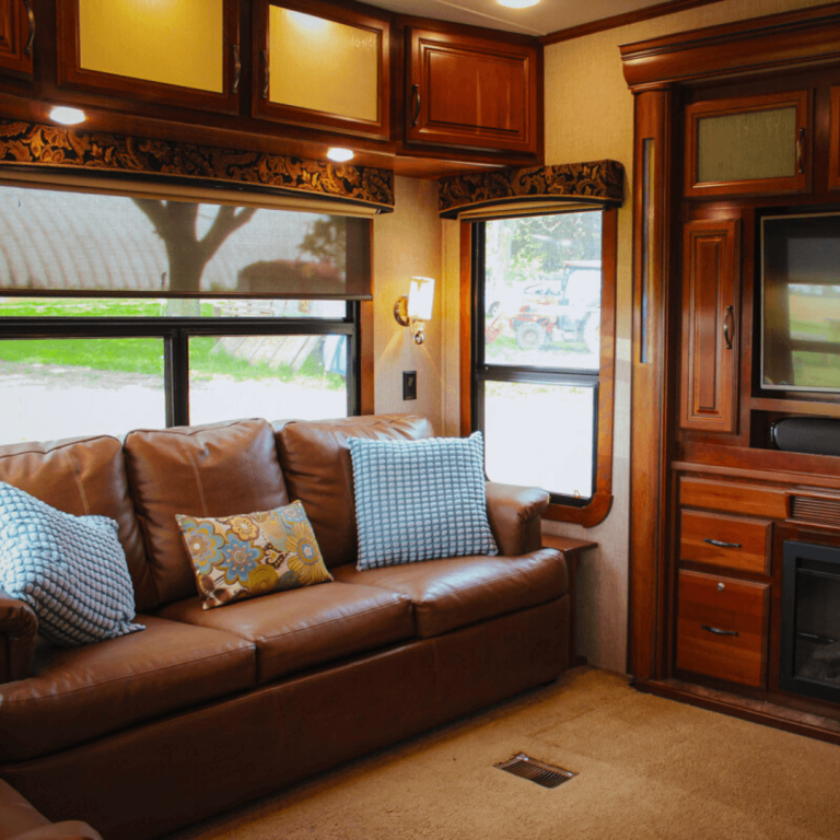 Spacious RV living room with large windows and a leather pull-out sofa at Udderly Ridiculous Farm Life’s Farm Glamping experience.