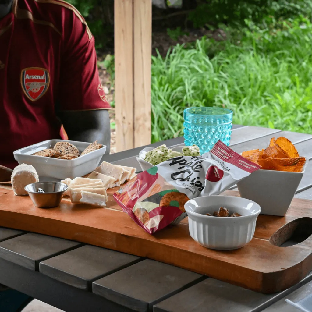 A close-up of a charcuterie board featuring crackers, cheese, apple chips, and other snacks, served during the Alpaca Lunch Picnic at Udderly Ridiculous Farm Life.