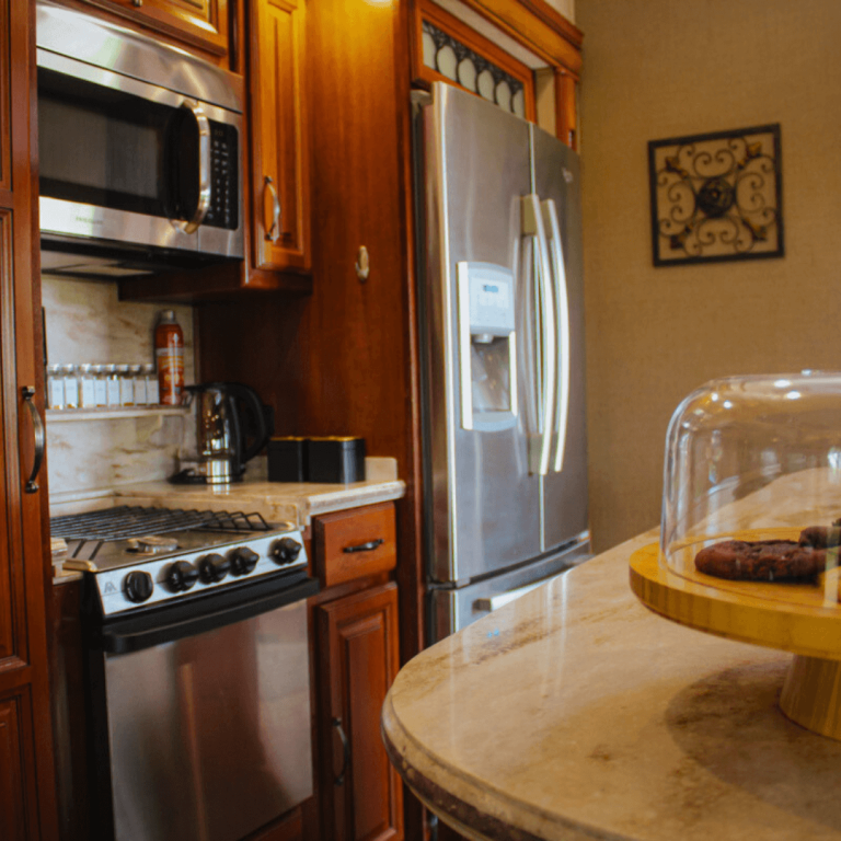 Fully equipped kitchen inside the luxury RV at Udderly Ridiculous Farm Life, featuring a fridge, stove, microwave, coffee maker, and spacious counter with treats.