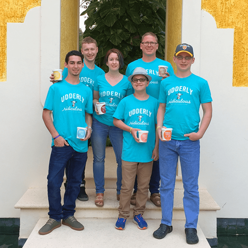 Cheryl and Greg with their four boys, all wearing Udderly Ridiculous t-shirts and holding cups of Udderly Ridiculous goat milk ice cream. A family united by passion, adventure, and the farm-to-table experience.